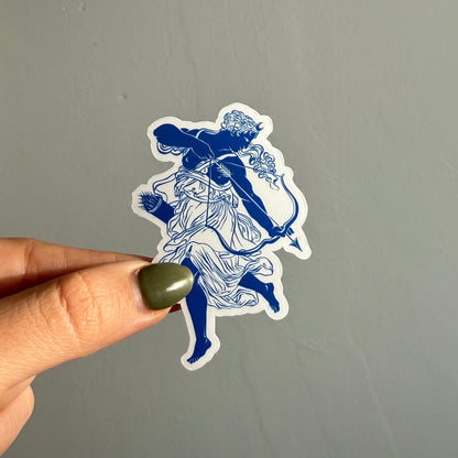 artemis in full motion — bow drawn, robes flowing — illustrated in a striking blue & white style inspired by ancient greek art