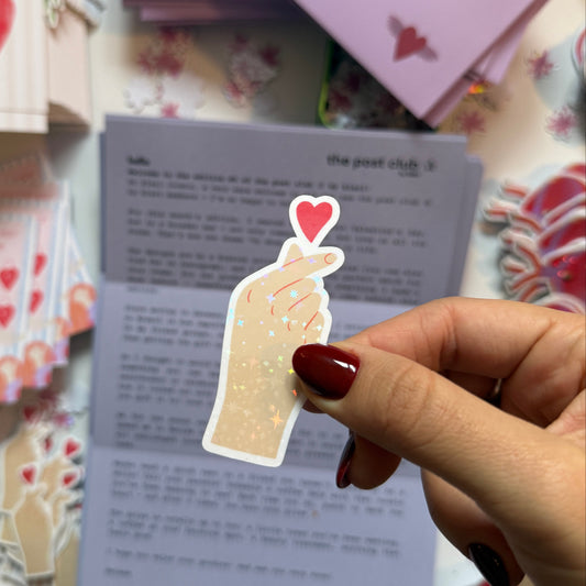 Cute holographic sticker of a hand doing a finger heart with a little red heart on top. Waterproof, scratch resistant, approx. 3x6cm. Perfect for journals, laptops & more.