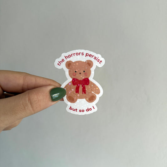  Cute holographic teddy bear sticker that says "the horrors persist but so do I". Waterproof, scratch resistant. Perfect for journals, laptops & more.